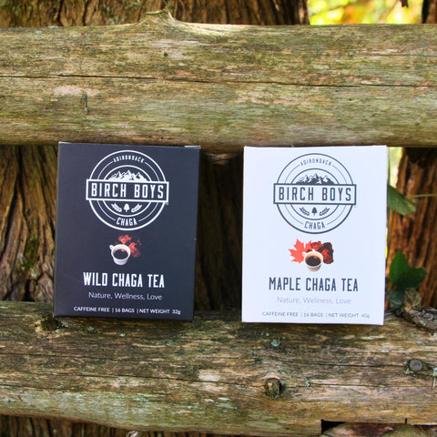 Two boxes of Birch Boys Chaga tea on a wooden fence with a natural background.