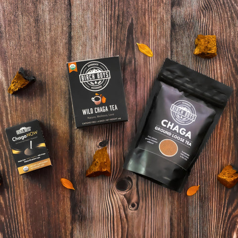 Chaga tea products on a wooden surface with chaga mushrooms and flower petals.