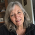 Gift wrap portrait of a smiling woman with gray hair wearing a dark top.
