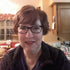 Gift wrap portrait of a woman with short hair and glasses in a cozy indoor setting.