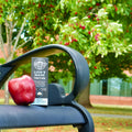 Box of Lion's Mane Tincture on a bench with an apple, surrounded by greenery.