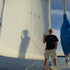 Man on a sailboat holding a beer with a large sail in the background
