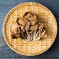 Maitake mushrooms on a woven bamboo tray against a wooden background
