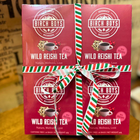 Three boxes of Birch Boys Wild Reishi Tea with a decorative ribbon on a blurred background.