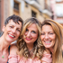 Three women smiling together outdoors with a blurred background